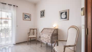 Een kamer met een houten stoel, een houten kast met lades en een wandlamp.