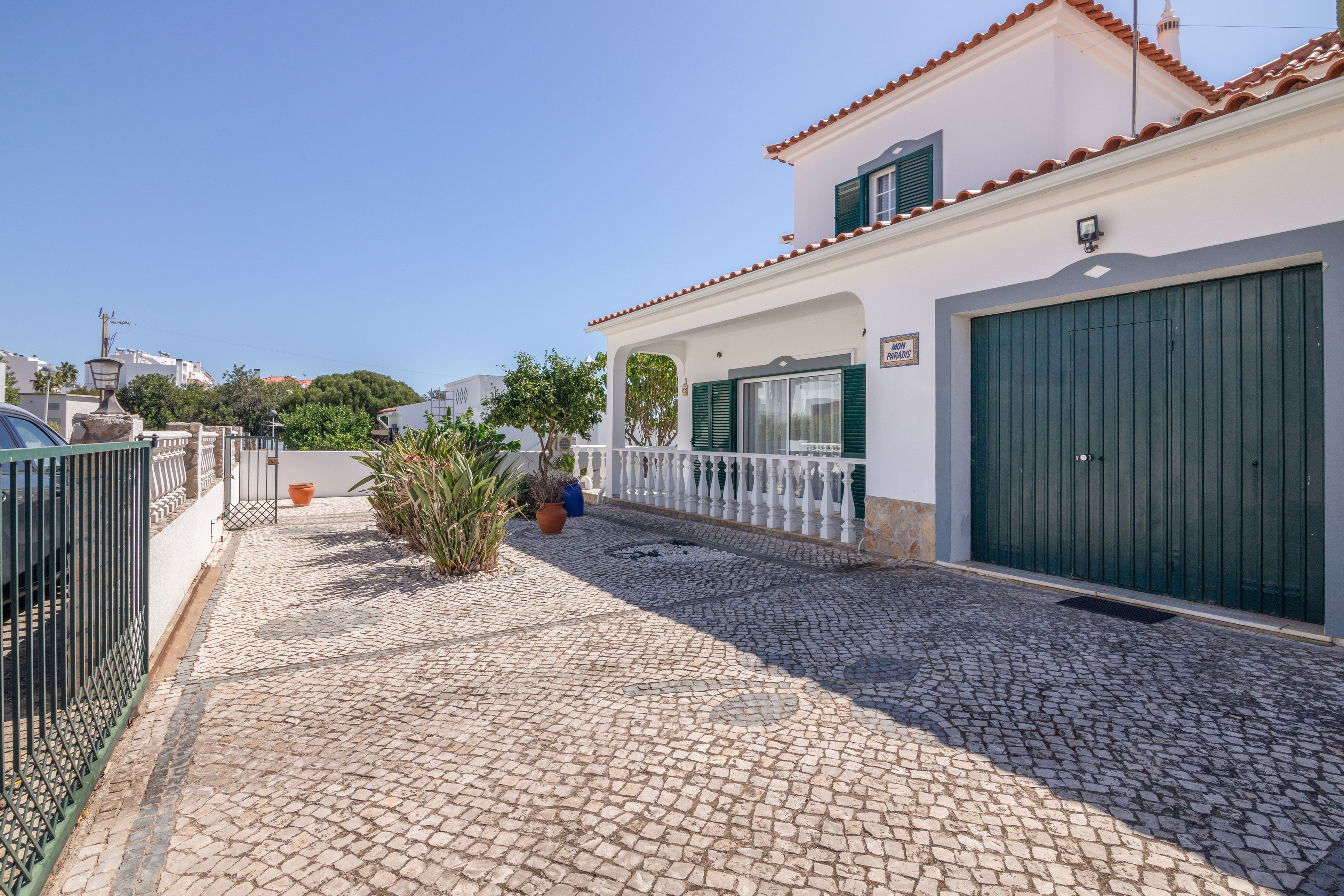 Una propiedad residencial con camino de adoquines, entrada portón cerrado y garaje.