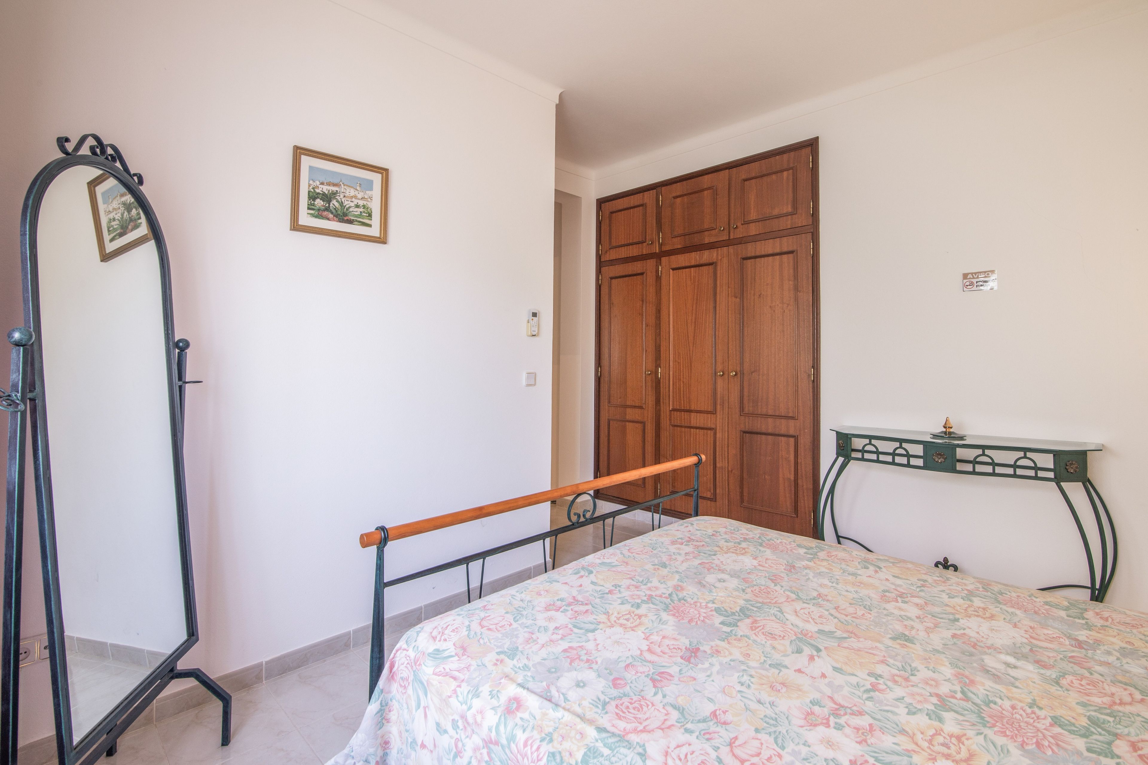 Een slaapkamer met een bed, een garderobe, een kaptafel en een spiegel.
