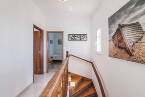 A staircase with wooden railings leading to a bedroom with a bed and a window.