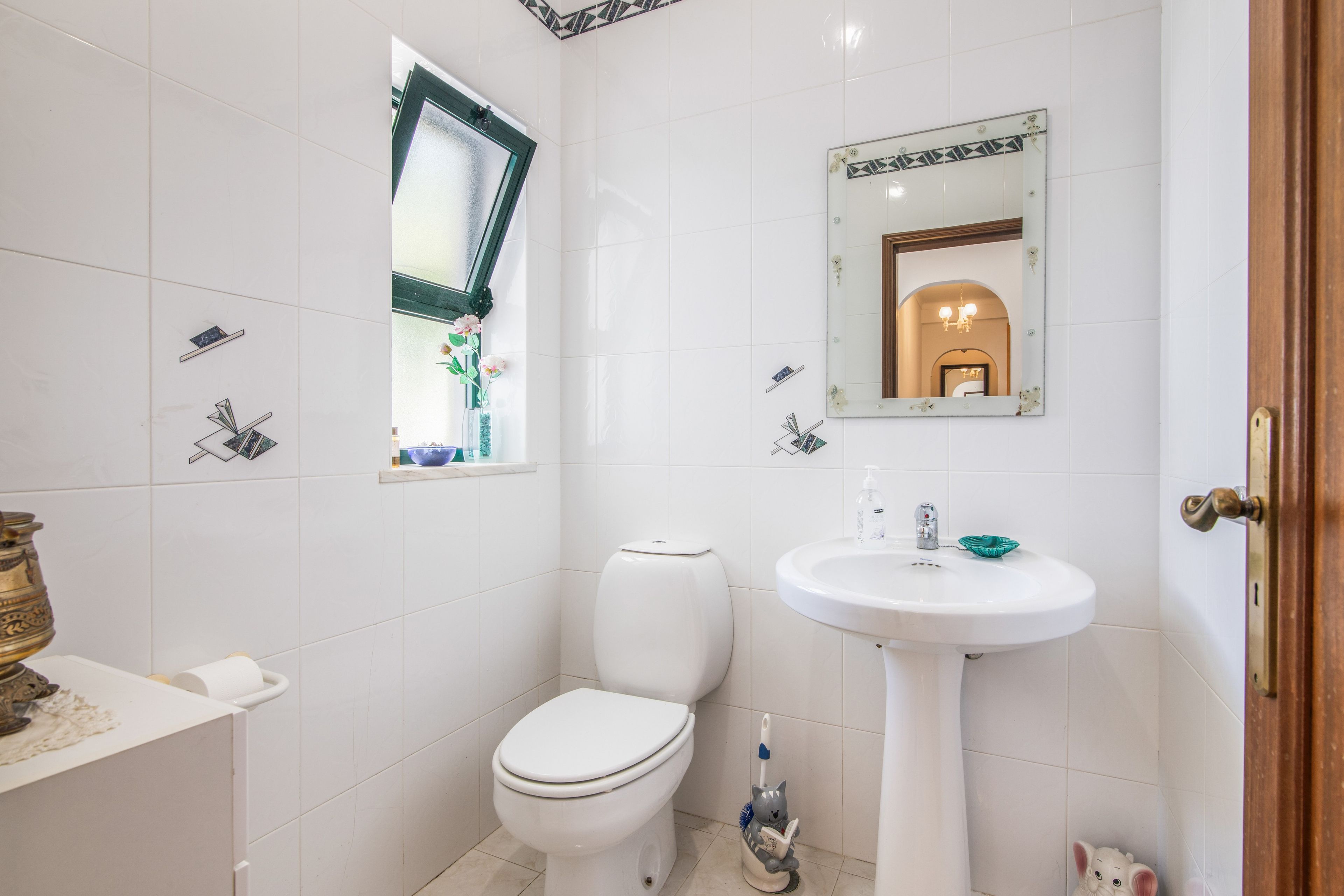 A bathroom with a toilet, sink, and a mirror.