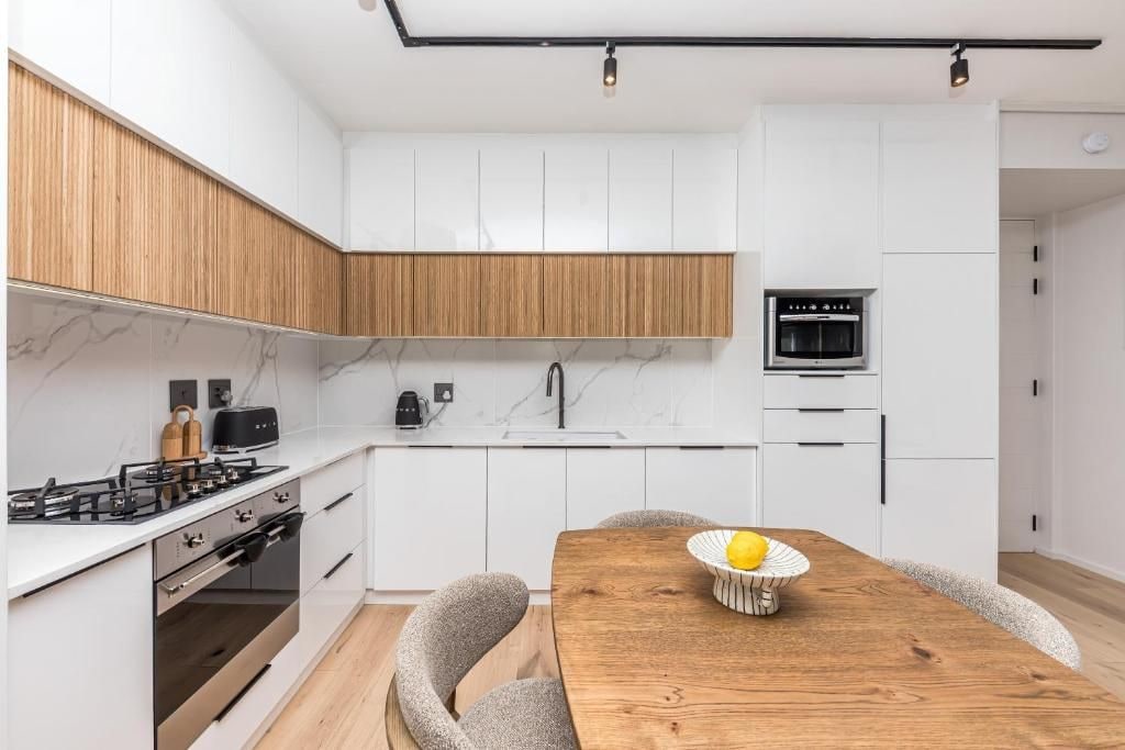 A modern kitchen with white cabinets, a wooden countertop, and a built-in oven.