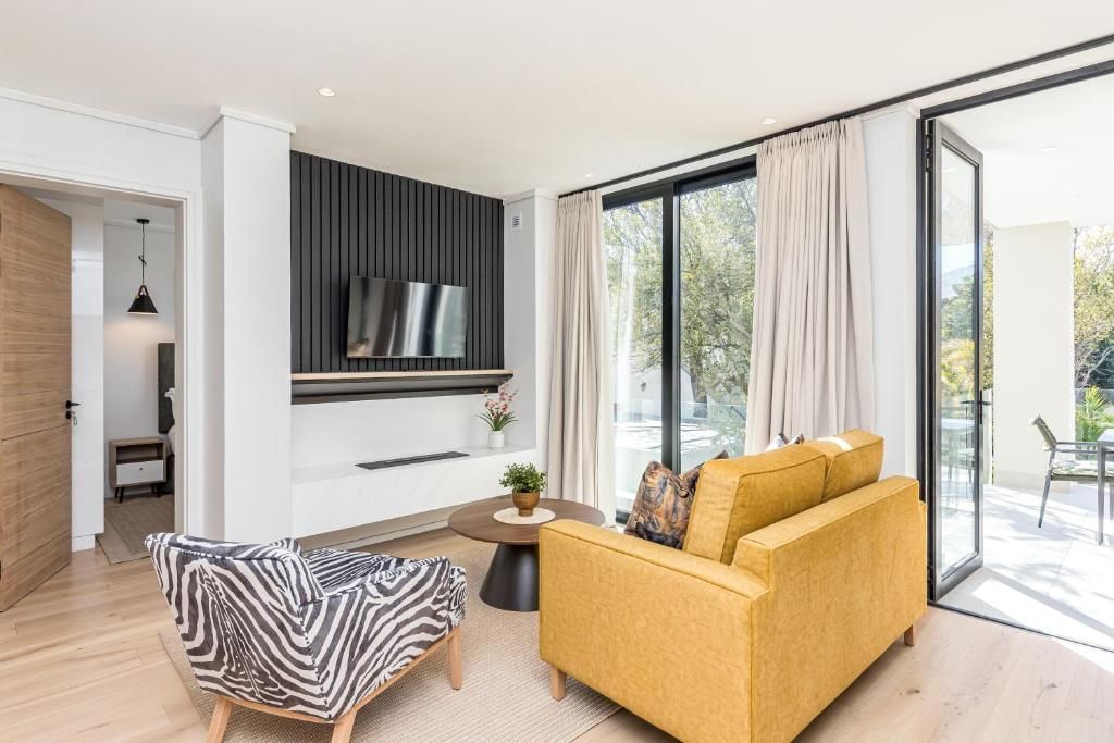 A modern living room with a sofa, a chair, a TV mounted on the wall, and a large sliding glass door leading to an outdoor area.