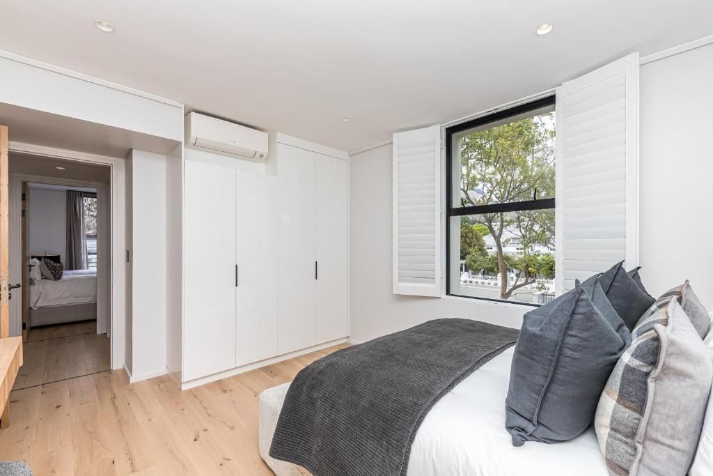A bedroom with a bed, a window with shutters, a wardrobe, and a door leading to another room.