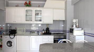A kitchen with white cabinets, a washing machine, a coffee maker, and a microwave.