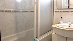 Un bagno con doccia, lavandino e specchio.