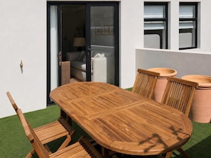 A wooden dining table with chairs, a sliding glass door, and a window with a view of a room. - Superior One-bedroom Garden - Unit 4 (Stellenbosch)
