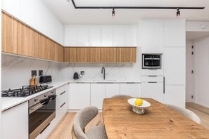 A modern kitchen with white cabinets, a wooden countertop, and a built-in oven. - Superior One-bedroom Garden - Unit 4 (Stellenbosch)