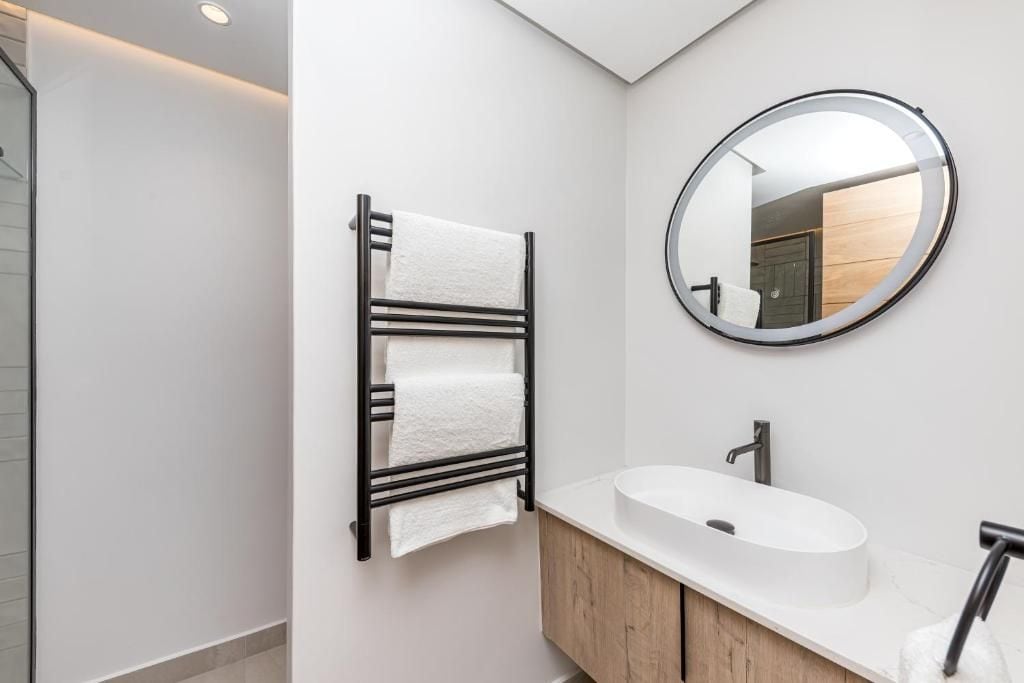 Ein modernes Badezimmer mit einem weißen Waschbecken, einer Holzkommode und einem Handtuchhalter mit zwei Handtüchern.