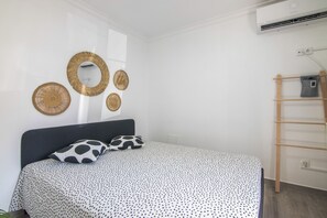 A bedroom with a bed, a wall-mounted air conditioner, and a wooden ladder.