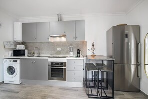 Una cocina moderna con electrodomésticos de acero inoxidable, horno empotrado y cafetera.