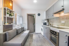 A compact kitchen with a built-in oven, a washing machine, and a microwave. - Holiday Home 'Little Paradise' with Shared Terrace, Wi-Fi and Air Conditioning (Castro Marim)