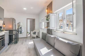A modern kitchen with a dining area, a sofa, and a window with a view.