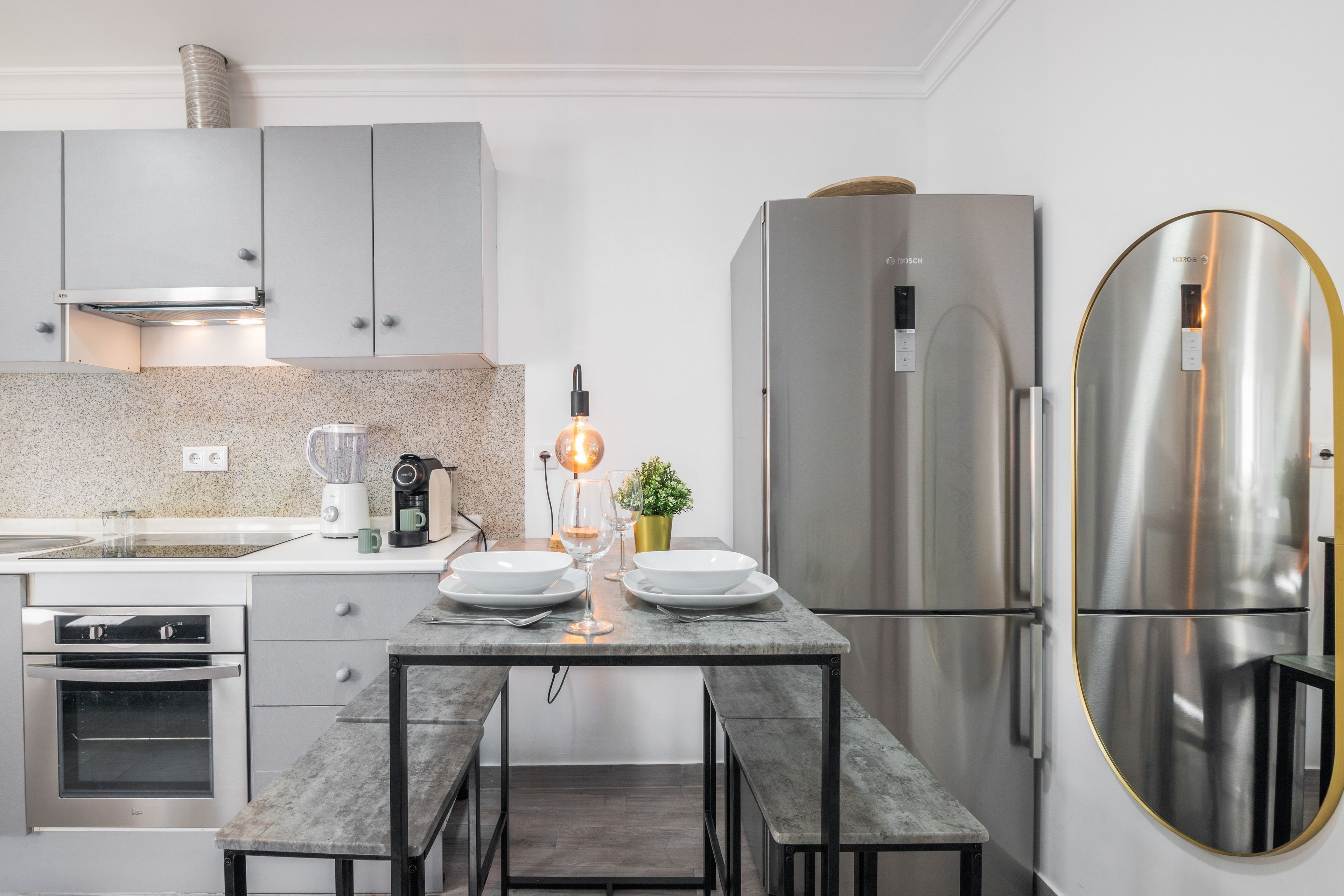 Una cocina moderna con horno empotrado, refrigerador de acero inoxidable y una mesa de comedor con sillas.