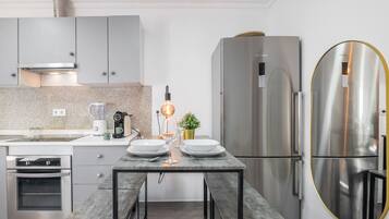 Una cocina moderna con horno empotrado, refrigerador de acero inoxidable y una mesa de comedor con sillas.