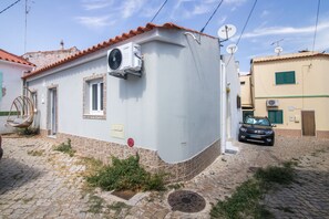 Un edificio residencial con techo de tejas rojas, pared exterior blanca y una ventana.