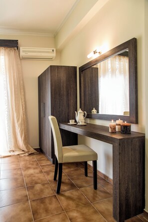 A bathroom with a dark wood vanity, a white chair, a mirror, and a lit candle on the counter.