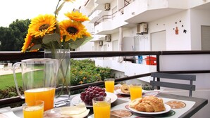 Une table de petit-déjeuner ornée d’un vase rempli de tournesols, d’une assiette de raisins, de croissants et de verres de jus d’orange.