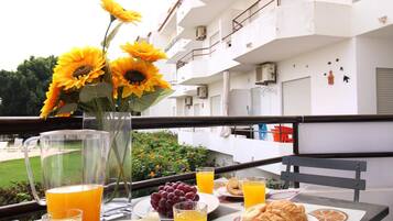 Una mesa de desayuno con un jarrón de girasoles, un plato de uvas, croissants y vasos de jugo de naranja.