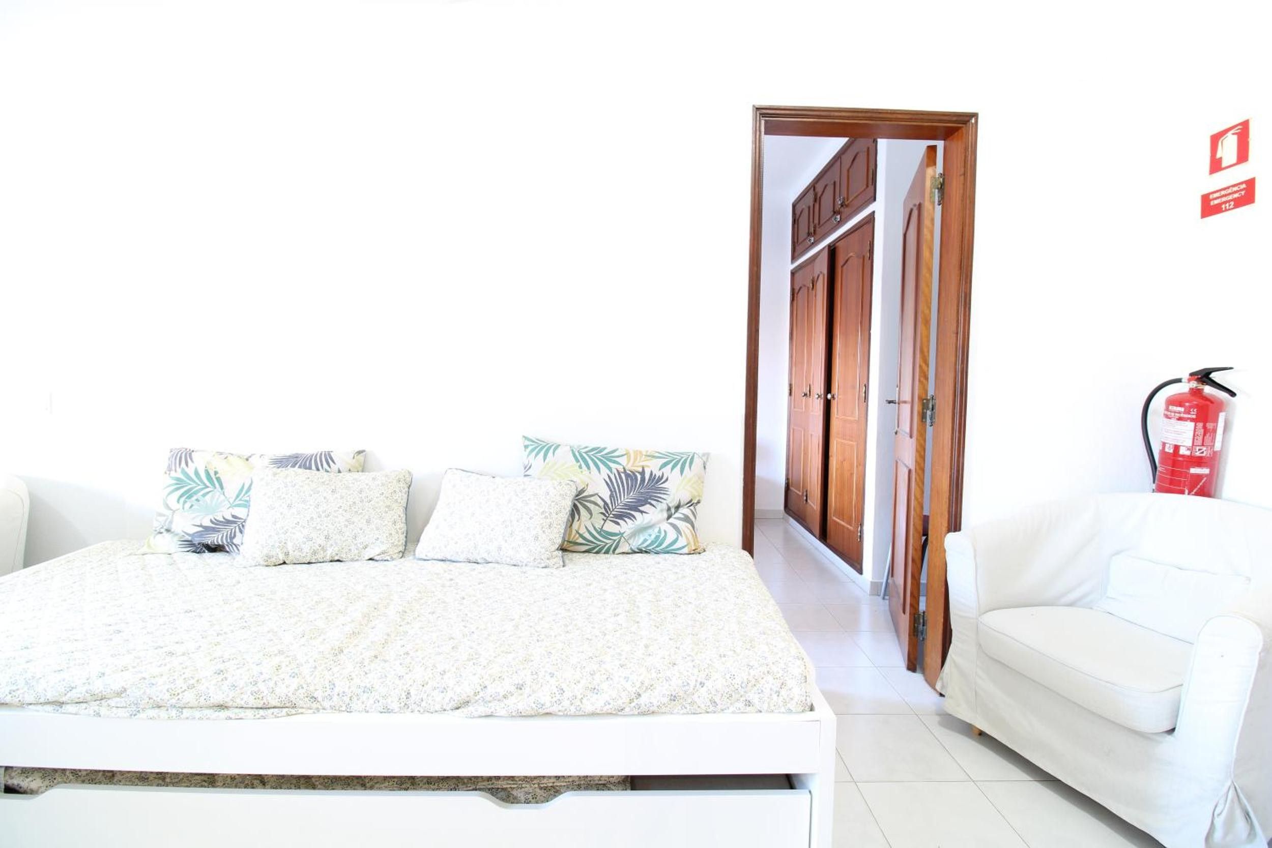Un dormitorio con una cama, un sofá blanco y una puerta que da a otra habitación.