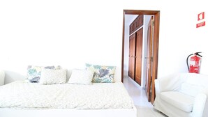 Une chambre à coucher avec un lit, un canapé blanc et une porte qui donne sur une autre pièce.