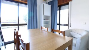 Un coin repas avec une table et des chaises en bois, un buffet blanc et des rideaux bleus.
