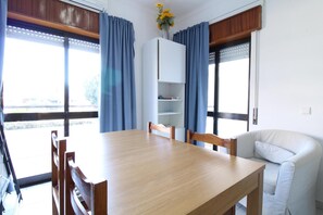 Un comedor con una mesa y sillas de madera, un armario blanco y cortinas azules.