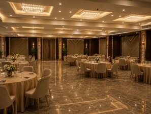 A spacious banquet hall with round tables, elegant chandeliers, and a polished marble floor. - Crestmont Sunshine Hotel (Uttarakhand)