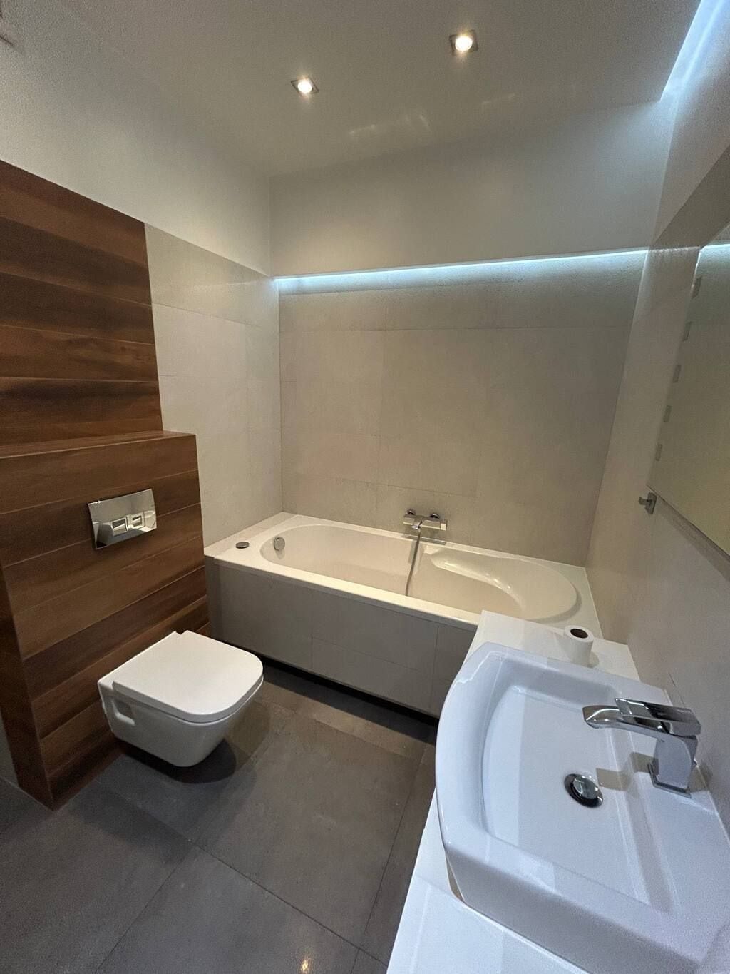 A modern bathroom with a bathtub, toilet, and sink.