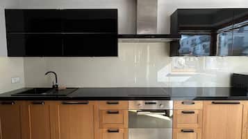 A modern kitchen with a black countertop, wooden cabinets, and stainless steel appliances.