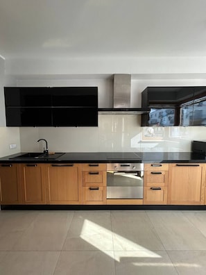 Een moderne keuken met een zwart aanrecht, houten kastjes en roestvrijstalen apparatuur.
