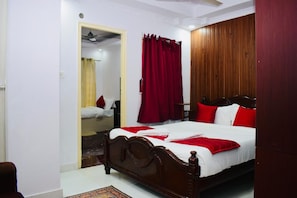 Une chambre à coucher avec un lit en bois, des rideaux rouges et un miroir.