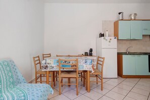 A compact kitchen with a dining table, chairs, a refrigerator, and a coffee maker. - Gamm Simius Home Holiday 1 (Villasimius)