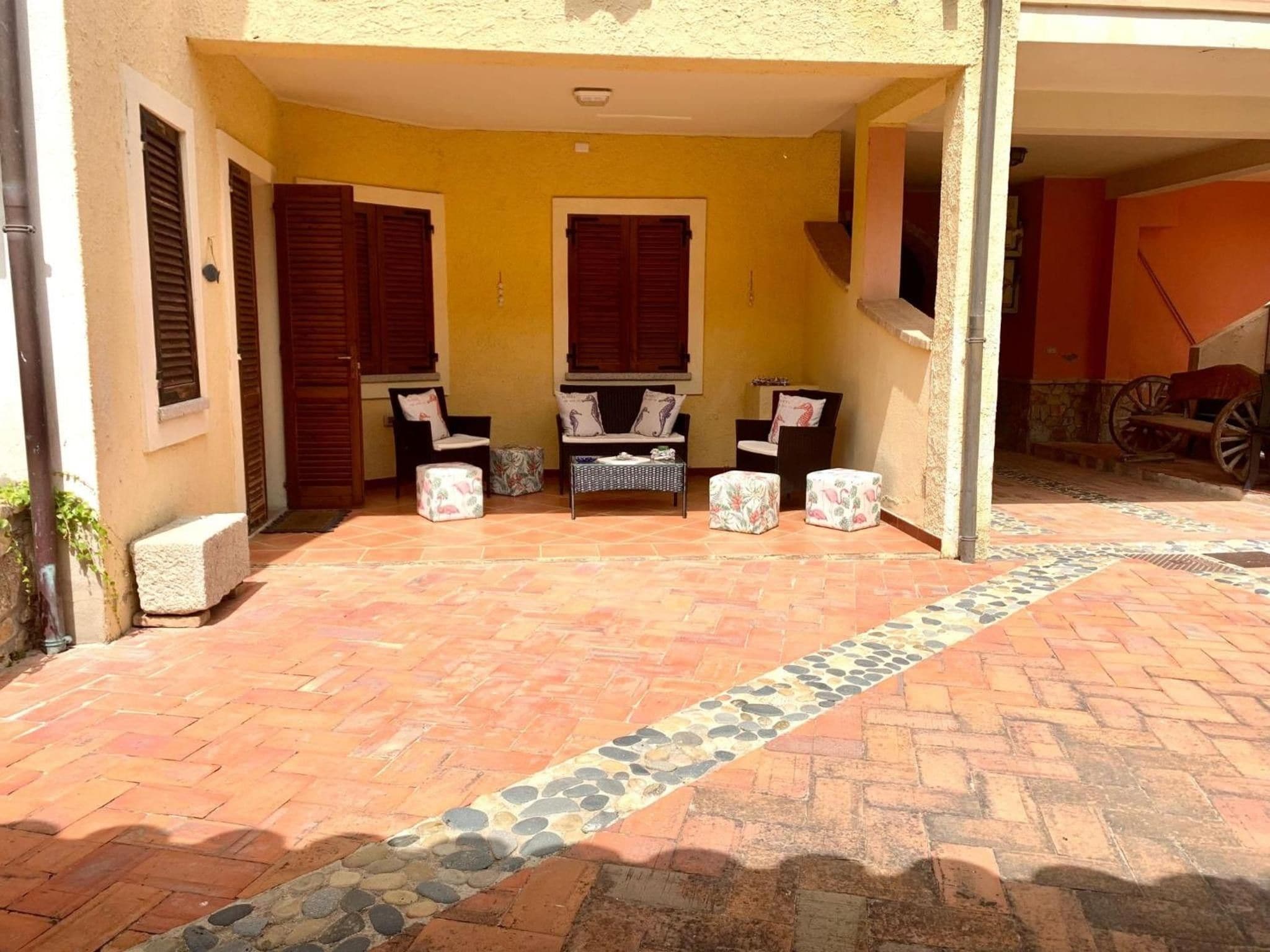 Un área de patio techada con piso de baldosas, dos sofás y una mesita.
