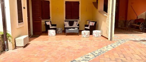 Un área de patio techada con piso de baldosas, dos sofás y una mesita.