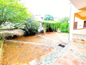 Une cour avec un sol en briques, une petite fontaine et un espace de repos abrité.