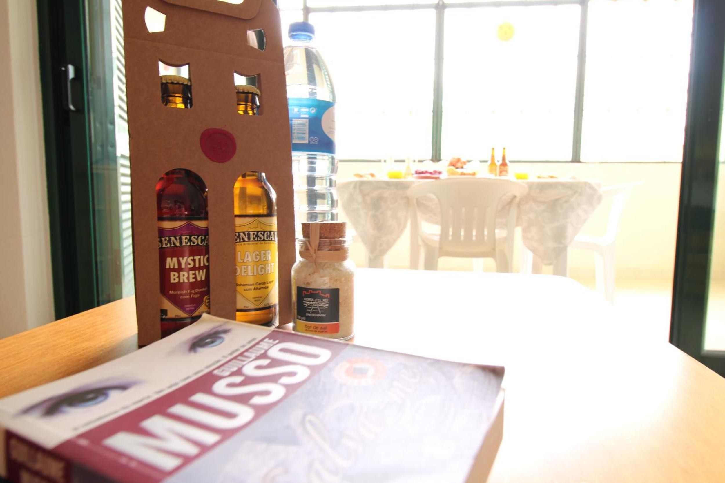 Una mesa con un libro titulado 'MUSSO' y dos botellas de cerveza, una botella de agua y un tarro de sal.