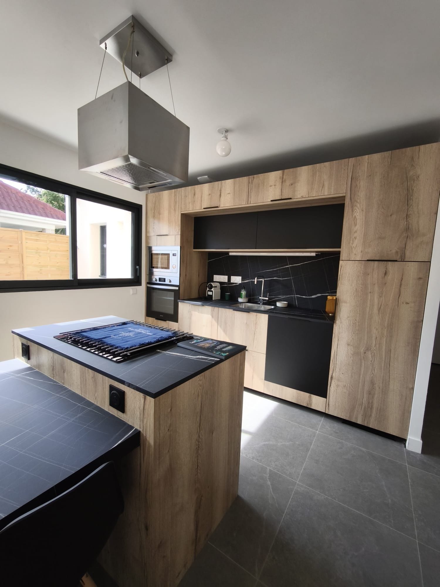A modern kitchen with wooden cabinetry, a central island, and a built-in oven.