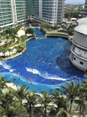 A large indoor swimming pool surrounded by palm trees and modern buildings. - 2BR Modern Boho Suite (Parañaque)