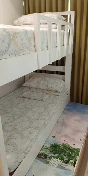 A bunk bed with floral bedding and a view of a residential area through the window. - 2BR Modern Boho Suite (Parañaque)
