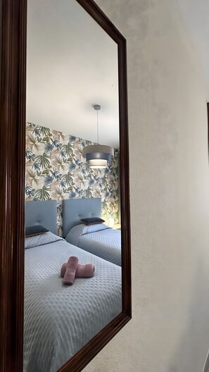 Ein Schlafzimmer mit zwei Betten, einem Spiegel und einer Deckenleuchte.