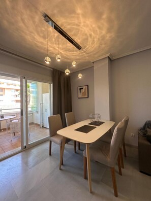 A modern dining area with a glass door leading to an outdoor patio, a table with chairs, and pendant lighting. - Sea, comfort and tranquillity — right by the beach (Denia)