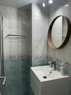 A bathroom with a shower, a sink, a mirror, and decorative tiles. - Sea, comfort and tranquillity — right by the beach (Denia)