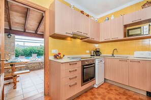 Eine Küche mit Holzausstattung, einer Mikrowelle, einer Kaffeemaschine und einem Geschirrspüler.