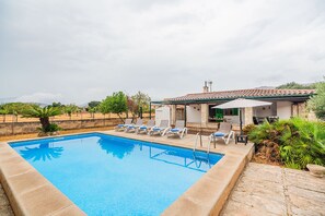 Une piscine avec des chaises longues et un petit bâtiment doté d’un toit en tuiles.