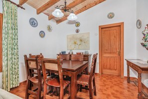 Ein Essbereich mit Holztisch und Stühlen, einer Deckenleuchte sowie dekorativen Tellern an der Wand.