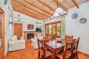 Un coin repas avec une table et des chaises en bois, une cheminée et un téléviseur.
