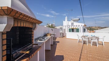 En takterrass med en grill, utomhusmöbler och utsikt över det omgivande landskapet.