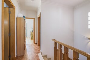 A hallway with wooden doors, a tiled floor, and a staircase with wooden railings. - Villa 'Grandvale' with Private Terrace, Wi-Fi and Air Conditioning (Castro Marim)