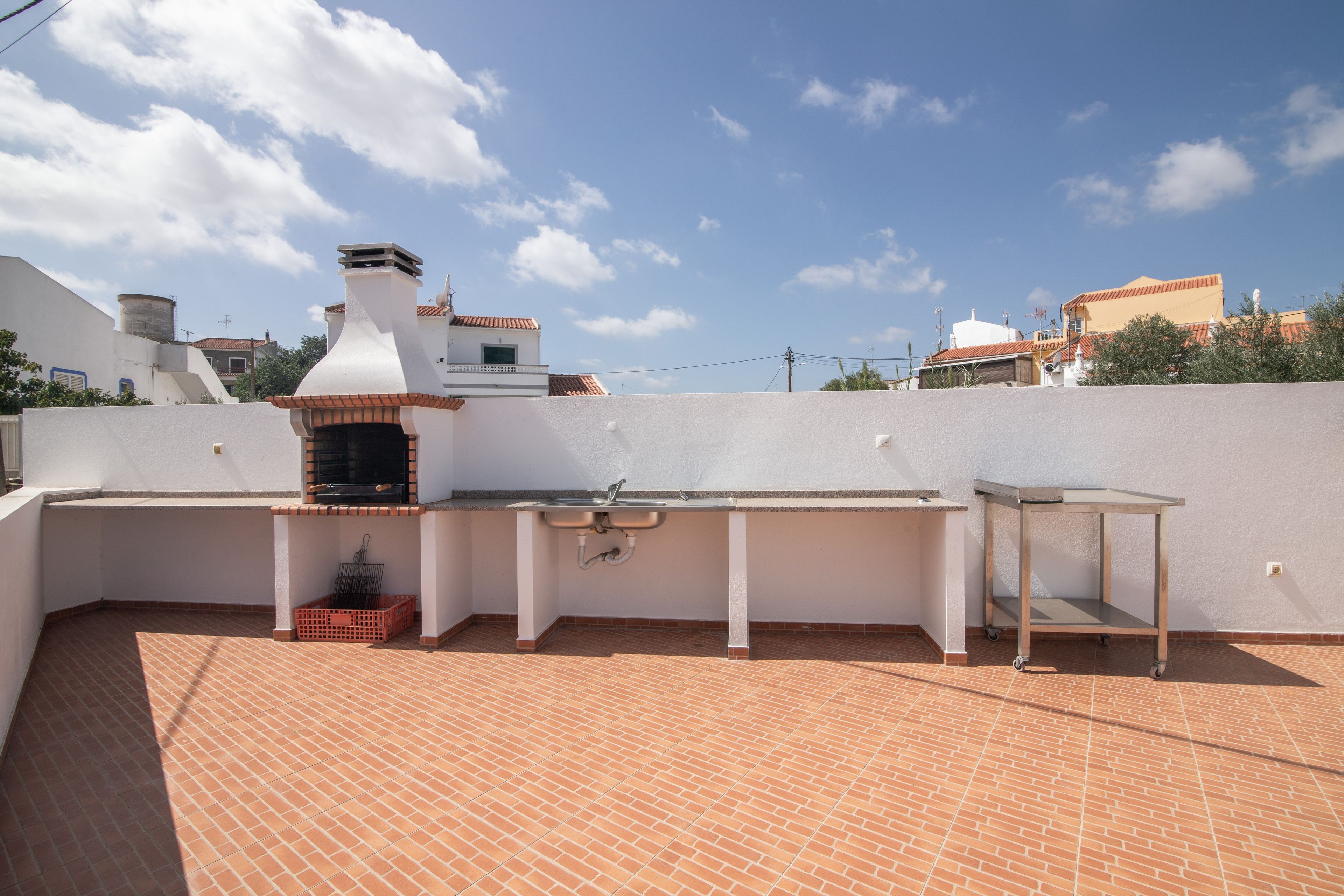 Una terraza en la azotea con una parrilla, un lavamanos y una pequeña mesa.